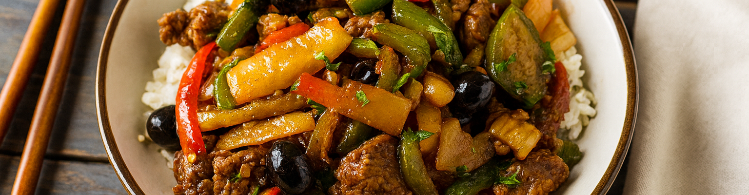 Beef and vegetable stir-fry served over white rice with bell peppers, zucchini, pineapple, and black olives in a savory sauce.