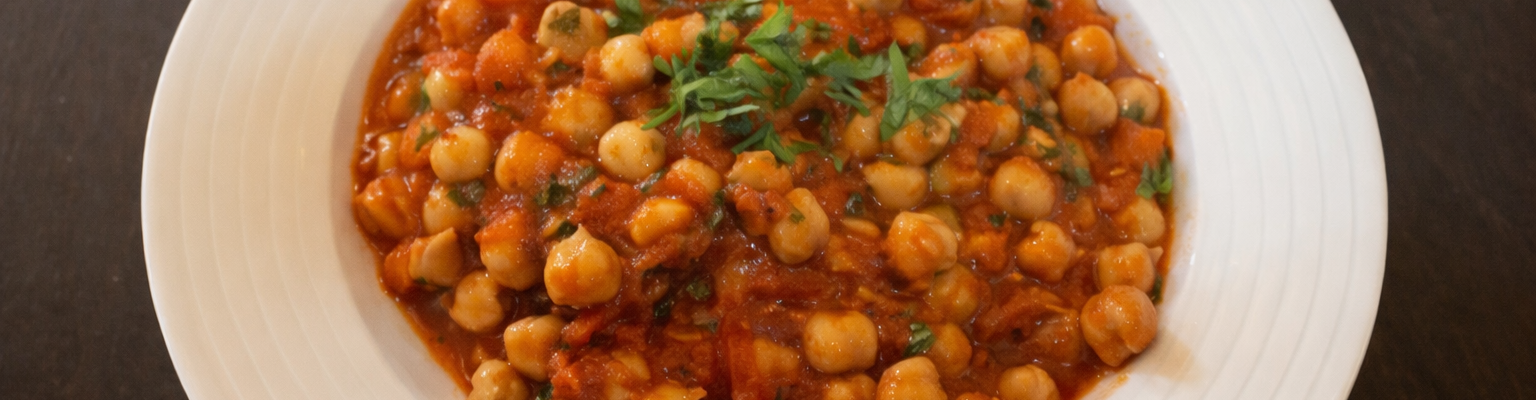 Chickpea stew in a tomato-based sauce, garnished with fresh herbs.