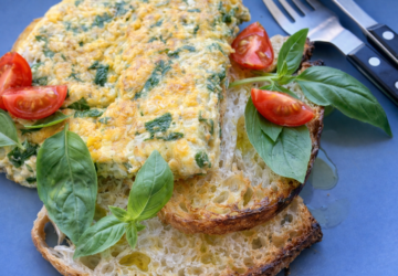 A spinach and feta omelette served on toasted sourdough with fresh basil and tomato.